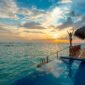 Woman enjoying a stunning sunset at a luxury Maldives resort's infinity pool.